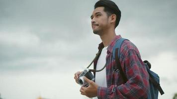 Asian man takes pictures with a film camera in Thailand.