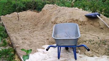 A pile of earth and a cart. Cleaning of fertile soil with a garden cart. photo