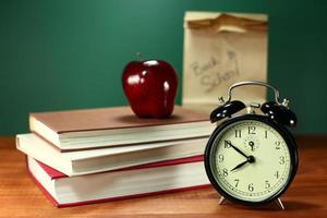 almuerzo, manzana, libros y reloj en el escritorio en la escuela. foto