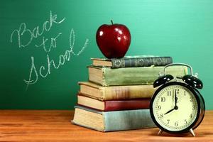 School Books, Apple and Clock on Desk at School photo