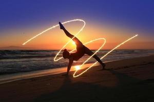 Joven bailarina experta en la playa durante la puesta de sol foto