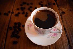 Cup of coffee and beans on an old wooden table photo