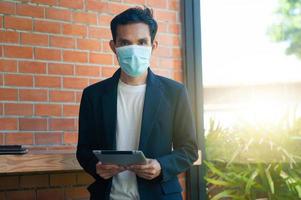 Man wear face mask using Tablet technology photo