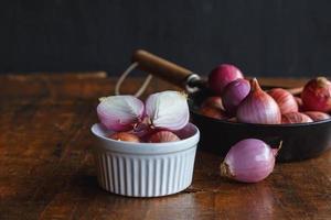 Fresh red onion in bowl on wood table. photo