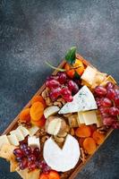 Big cheese board with appetizer assortment. Grape, cheese, nuts, jam and bread. photo