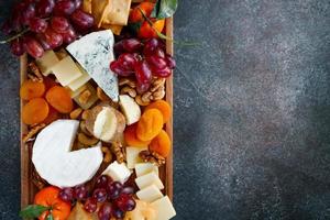 Big cheese board with appetizer assortment. Grape, cheese, nuts, jam and bread. photo