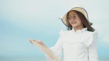 schattig Aziatisch meisje wandelen op het strand aan het strand. langzaam liet ze de zandkorrel uit haar hand los. video