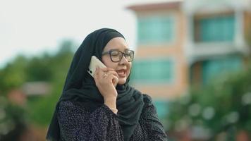 Mujer musulmana asiática de pie y hablando por teléfono celular