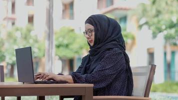 mulheres muçulmanas bonitas sentadas do lado de fora trabalhando de acordo com o slogan formulário de trabalho para casa video