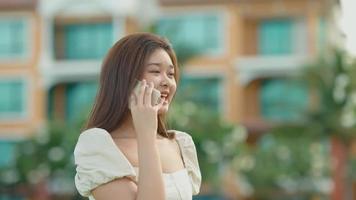 jolie fille asiatique, elle utilise son téléphone portable pour parler à ses amis avec plaisir. video