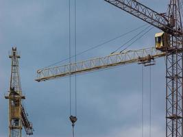 Yellow construction cranes against cloudy sky background photo