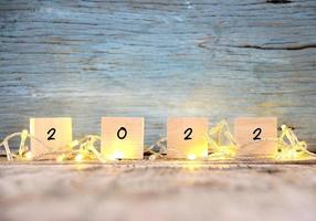 Happy New year 2022 on brown wood table and blur abstract bokeh light photo