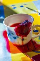 Red tea and tea bags poured out of white cup photo