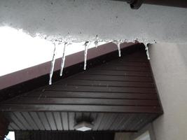 Winter icicles hang from the roof of the building photo