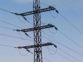 Líneas eléctricas de alta tensión y torres sobre fondo de cielo azul foto