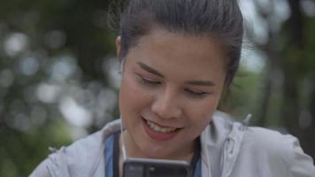 coureur de fitness femme asiatique utilisant un téléphone portable en écoutant de la musique dans un parc public.