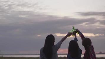 mujer asiática amigos felices acampando en la naturaleza divirtiéndose juntos bebiendo cerveza y tintineando vasos. video
