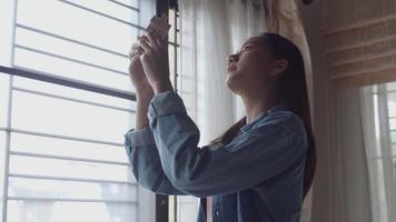 arquiteto freelance mulher asiática segurando modelo de pé em casa ao lado da janela no escritório em casa. video