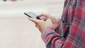 asiatisk man som går och använder smartphone som kontrollerar sociala medier på gatan i thailand. video