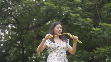 Young Asian woman playing soap bubbles and having fun outdoors at a public park. video