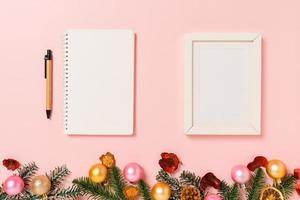 Minimal creative flat lay of winter christmas traditional composition and new year holiday season. Top view open mockup black notebook for text on pink background. Mock up and copy space photography. photo