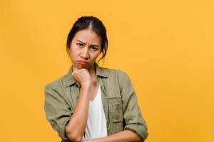 Young Asia lady with negative expression, excited screaming, crying emotional angry in casual clothing and look at camera isolated on yellow background with blank copy space. Facial expression concept photo