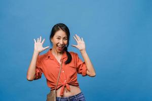 Young Asia lady feel happiness with positive expression, joyful surprise funky, dressed in casual cloth and looking at camera isolated on blue background. Happy adorable glad woman rejoices success. photo