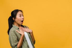Young Asia lady feel happiness with positive expression, joyful surprise funky, dressed in casual cloth isolated on yellow background. Happy adorable glad woman rejoices success. Facial expression. photo