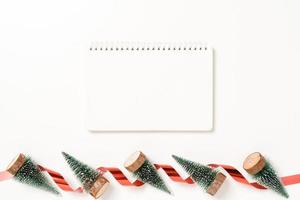 Minimal creative flat lay of winter christmas traditional composition and new year holiday season. Top view open mockup black notebook for text on white background. Mock up and copy space photography. photo