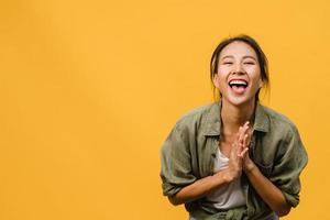 Young Asia lady with positive expression, smile broadly, dressed in casual clothing and looking at camera over yellow background. Happy adorable glad woman rejoices success. Facial expression concept. photo