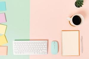 Creative flat lay photo of workspace desk. Top view office desk with keyboard, mouse and open mockup black notebook on pastel green pink color background. Top view mock up with copy space photography.