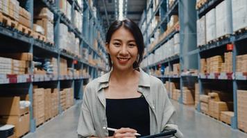Portrait of attractive young Asia businesswoman manager smiling charmingly looking at camera hold digital tablet stand in retail shopping center. Distribution, Logistics, Packages ready for shipment. photo
