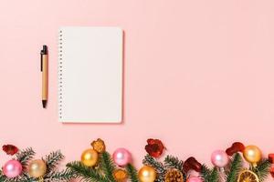 Minimal creative flat lay of winter christmas traditional composition and new year holiday season. Top view open mockup black notebook for text on pink background. Mock up and copy space photography. photo