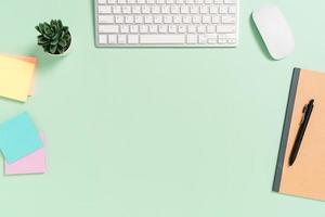 Minimal work space - Creative flat lay photo of workspace desk. Top view office desk with keyboard, mouse and book on pastel green color background. Top view with copy space, flat lay photography.