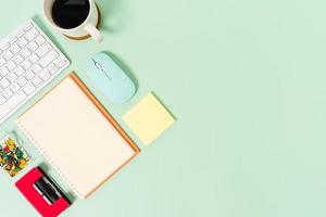 Creative flat lay photo of workspace desk. Top view office desk with keyboard, mouse and open mockup black notebook on pastel green color background. Top view mock up with copy space photography.
