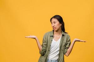 Retrato de joven asiática con expresión negativa, gritos emocionados, llorando emocionalmente enojado en ropa casual aislado sobre fondo amarillo con espacio de copia en blanco. concepto de expresión facial. foto