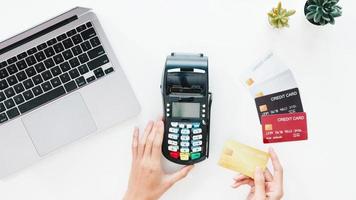 Top view of Asia lady using laptop online shopping with credit card pay the bill by payment terminal on table in living room at house. Working from home, social distancing, quarantine for coronavirus. photo