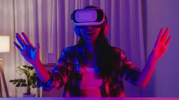 Asia lady wear VR game headset having fun experience wearable virtual augmented ar reality digital innovation technology happy moment New Year neon night party event celebration in living room at home photo