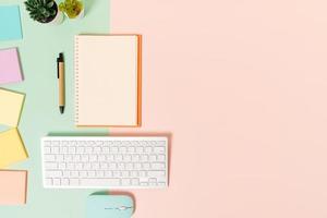 Creative flat lay photo of workspace desk. Top view office desk with keyboard, mouse and open mockup black notebook on pastel green pink color background. Top view mock up with copy space photography.