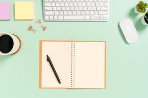 Creative flat lay photo of workspace desk. Top view office desk with keyboard, mouse and open mockup black notebook on pastel green color background. Top view mock up with copy space photography.