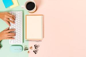 Creative flat lay photo of workspace desk. Top view office desk with keyboard, mouse and open mockup black notebook on pastel green pink color background. Top view mock up with copy space photography.