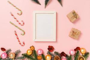 Minimal creative flat lay of winter christmas traditional composition and new year holiday season. Top view mockup black picture frames for text on pink background. Mock up and copy space photography. photo