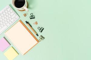 Creative flat lay photo of workspace desk. Top view office desk with keyboard and open mockup black notebook on pastel green color background. Top view mock up with copy space photography.