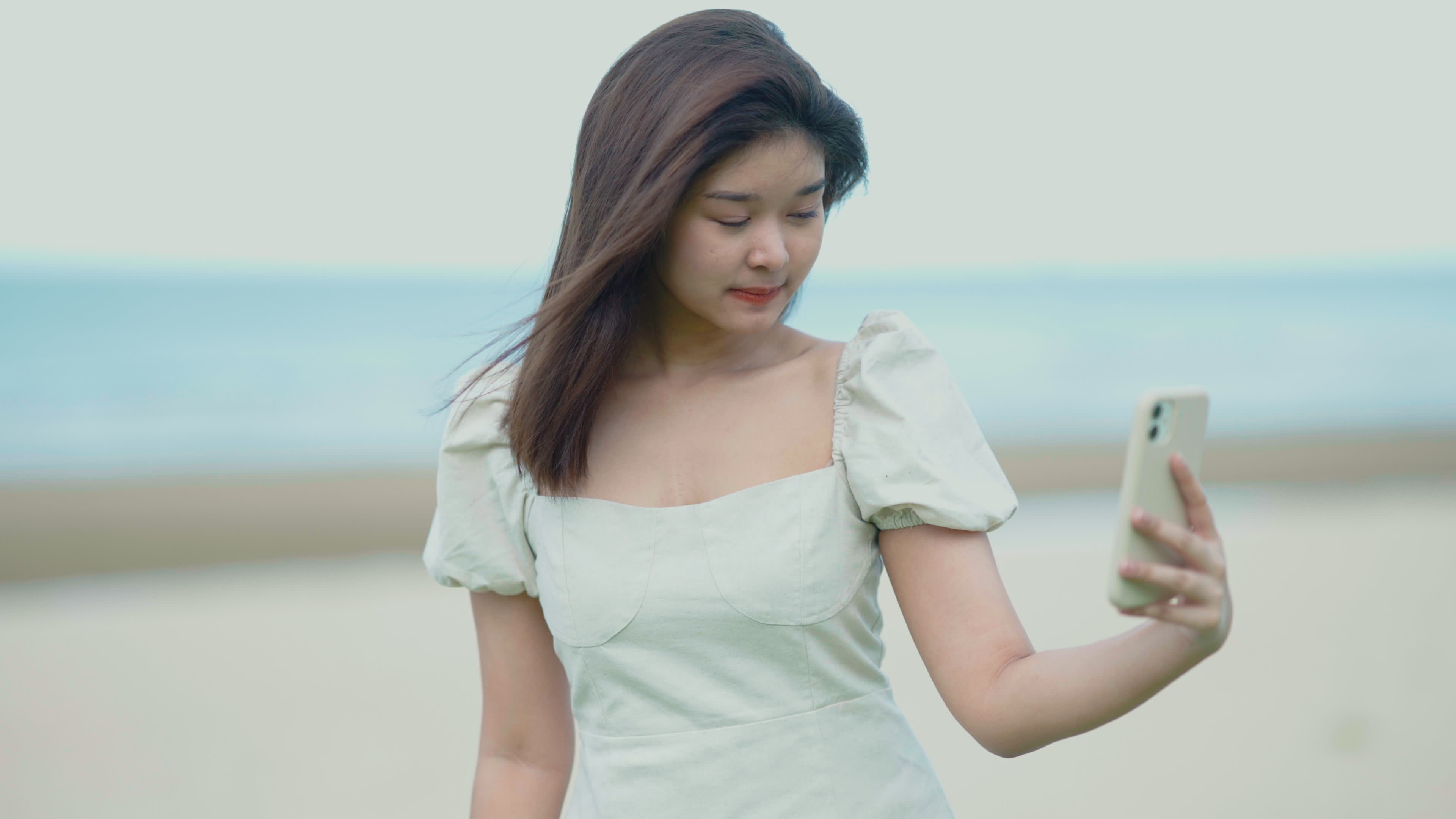 Asian girl using her cell phone at the beach