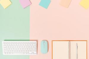 Creative flat lay photo of workspace desk. Top view office desk with keyboard, mouse and open mockup black notebook on pastel green pink color background. Top view mock up with copy space photography.