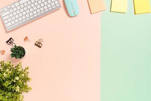 Minimal work space - Creative flat lay photo of workspace desk. Top view office desk with keyboard, mouse and adhesive note on pastel green pink color background. Top view with copy space photography.