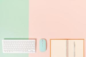 Creative flat lay photo of workspace desk. Top view office desk with keyboard, mouse and open mockup black notebook on pastel green pink color background. Top view mock up with copy space photography.