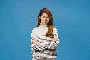 Young Asia lady with negative expression, excited screaming, crying emotional angry in casual clothing and looking at camera isolated on blue background. Happy adorable glad woman rejoices success. photo
