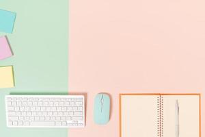 Creative flat lay photo of workspace desk. Top view office desk with keyboard, mouse and open mockup black notebook on pastel green pink color background. Top view mock up with copy space photography.