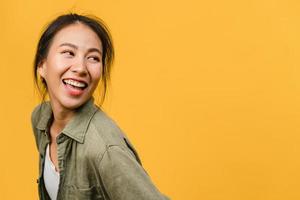 Portrait of young Asia lady with positive expression, smile broadly, dressed in casual clothing over yellow background. Happy adorable glad woman rejoices success. Facial expression concept. photo